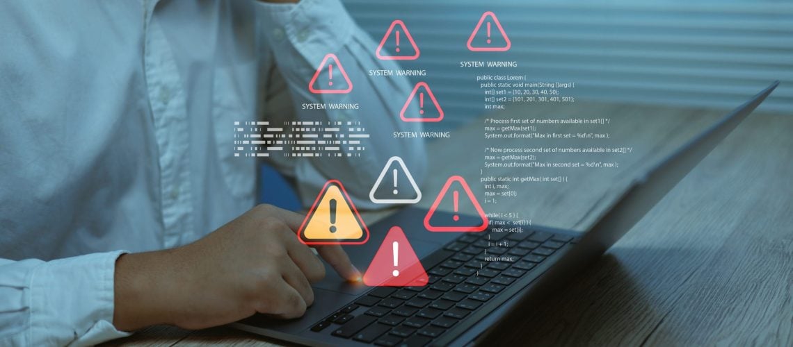 Business user facing system warning alerts error icons on laptop screen, symbolizing cybersecurity risk, software failure, data protection issues and digital technology problems.
